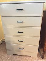 Front view of tall light grey 5-drawer dresser with dark blue pulls