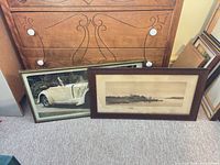 Both framed prints leaning against dresser