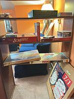 Shelf with multiple board game boxes including Scrabble, Risk, Boggle, Super Quiz II, Password, additional game boxes