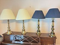 All four brass lamps on piano, two ivory and two navy shades