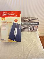 Both boxed items: Sunbeam heating pad and HoMedics massager