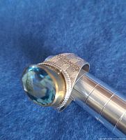 Side view of sterling silver ring showing blue topaz and band pattern