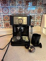 Front view of DeLonghi EC260BK espresso machine with portafilter and milk pitcher