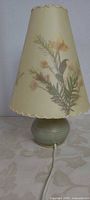 Full view of lamp unlit showing pressed leaf parchment shade and pottery base with cord