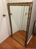 Full view of rectangular mirror leaning against wall