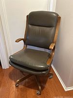 Front angled view shows leather upholstery, wood frame, casters