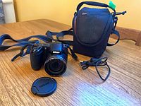 Camera with lens cap, USB cable and carrying case on table