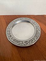Full view of pewter plate showing floral border and smooth center