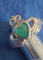 Front view showing Claddagh hands, crown and green heart stone