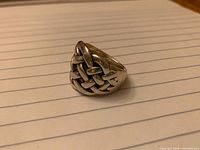 Front angle of sterling silver Celtic knot ring on lined paper