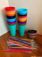 Stacked colourful tumblers, lids roll, straws bundled