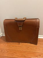 front angled view of brown leather briefcase showing handle and lock