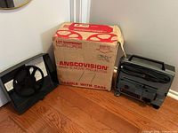 Projector, take-up reel with cover and original box displayed together