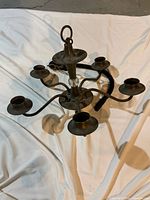 Full view of five-arm metal chandelier on white cloth