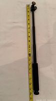 Pole fully extended beside measuring tape showing ~22 in length