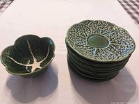 stack of eight saucers beside cabbage leaf bowl