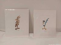 Both prints in protective sleeves side by side