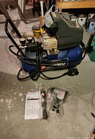 Campbell Hausfeld air compressor with attached hoses and packaged air tools