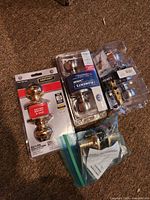 Four brass-finish door knob locksets, three in retail packaging and one loose in bag
