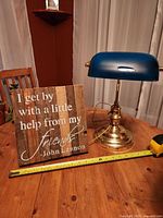 Brass banker desk lamp and wooden quote plaque on a round wooden table