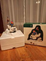 Figurine on styrofoam next to original box showing product image