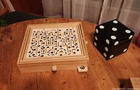 Wooden labyrinth and black dice cube closed on table