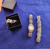 Ring in gift box, watch, and bracelet segment on fabric