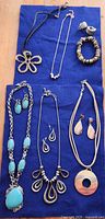 All 10 jewellery pieces arranged on blue fabric background