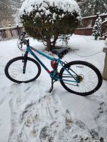 Full side view of teal Supercycle Nitro mountain bike in snow, showing frame, wheels, saddle and lock