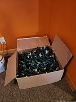 Open cardboard box filled with bundled green-wired LED light strings