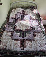 Full view of quilt on bed showing patchwork pattern and colors