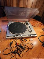 Technics turntable with dust cover open, platter, tonearm and cables visible