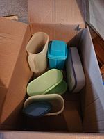 Cardboard box containing assorted Tupperware containers in various shapes and colors