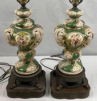 Front view of both porcelain lamps showing green and ivory relief decoration and metal bases