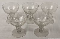 Five matching etched crystal coupe glasses displayed