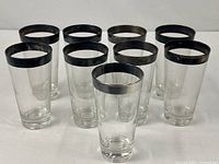 Nine clear glasses with silver rims arranged together