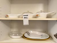 Shelf showing two handled CorningWare casseroles with lids, small round casserole with lid, two oval dishes, dinner plate and gold charger