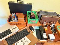 Overview of entire lot on tabletop showing keyboards, crates, briefcases, boxes, mouse, alarm clock and other items
