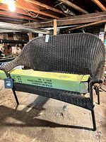 Full view of wicker loveseat with boxed patio umbrella resting on seat