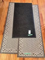 Overview of two patterned runners layered with black doormat on wooden floor