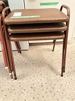 Stack of three brown vinyl stools showing metal frames