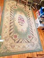 Full view of green and beige floral medallion rug on floor