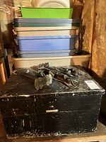 Stacked plastic totes, trunk base, cobbler parts on top