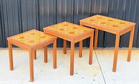 front view of three teak nesting tables showing tile tops