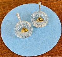 Two crystal salt cellars each with a sterling silver salt spoon inside, top view