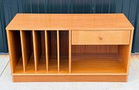 Front view showing five record slots, drawer, open bay, plinth base