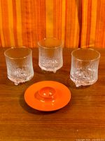 Three Ultima Thule glasses and orange egg cup on wood surface