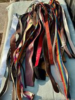 Full pile of assorted belts laid out on surface