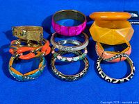 Group shot of all bangles and bracelets standing in rows on blue background
