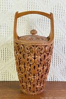 Front view of carved teak ice bucket showing full design